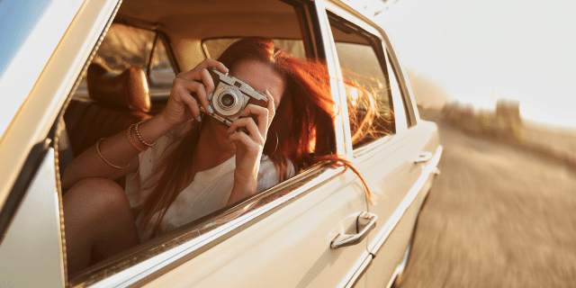 an image showing a woman in a car taking photos